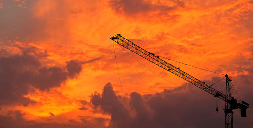 Low angle view of silhouette crane against sky during sunset