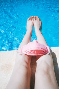 Low section of woman with mask sitting at poolside