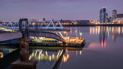 Illuminated ferry terminal over river in city