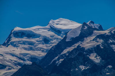 Scenic view of snowcapped mountains against blue sky