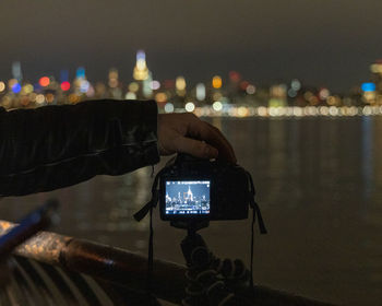 Digital composite image of hand holding illuminated smart phone at night