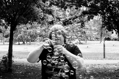 Portrait of man holding bubbles in park