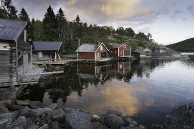 Houses and trees by lake against sky