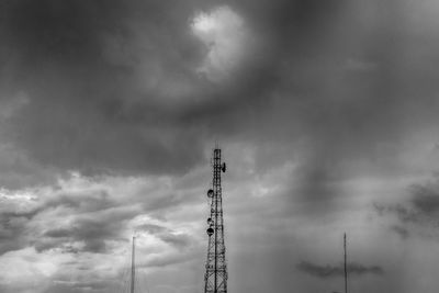 Low angle view of communications tower against cloudy sky