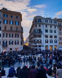 People on street amidst buildings in city against sky