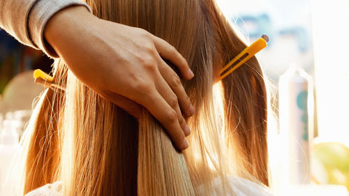 Cropped hands of female hairstylist styling girl hair