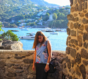 Woman standing by wall against bay
