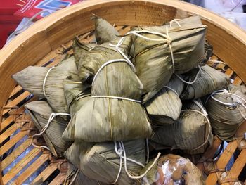 High angle view of leaves covered rice dumplings on wooden container