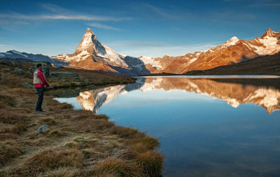 Scenic view of lake by snowcapped mountains against sky