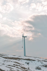 Windmill on snow covered field against sky