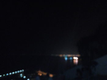 Defocused image of illuminated building against sky at night