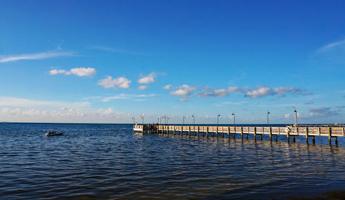 Pier over sea against blue sky