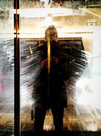 Reflection of man in illuminated mirror