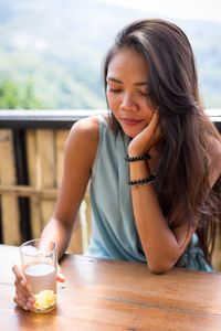 Close-up of young woman with drink on table