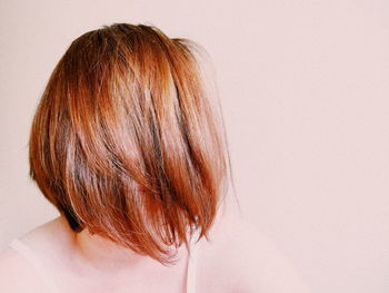 Close-up of woman with brown hair against beige background