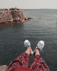 Low section of person on rock by sea