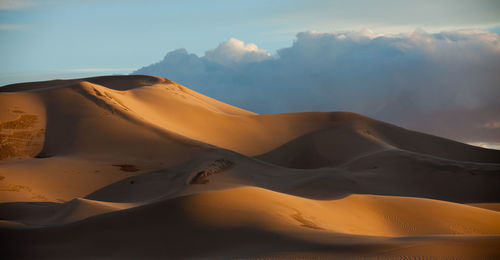 Sand dunes against sky during sunset