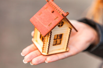 Close-up of hand holding toy against house