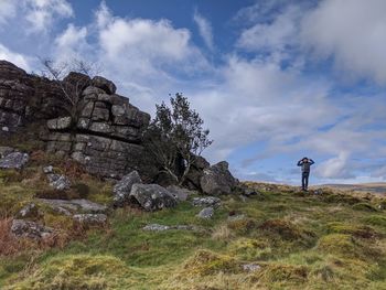 Man standing on rock against sky