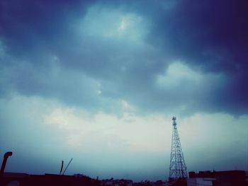 Low angle view of crane against cloudy sky