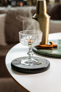 Close up of female hand burning cinnamon stick over drinking glass