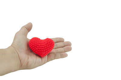 Close-up of hand holding heart shape over white background