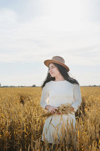 Side view of woman standing on field against sky