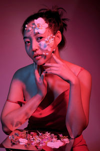 Portrait of young woman with petals on face