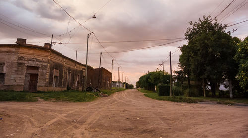 Road by trees and buildings against sky