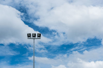 Low angle view of floodlights against cloudy sky