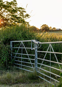 Fence on field against sky during sunset