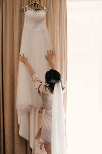 Midsection of woman holding umbrella standing against white curtain