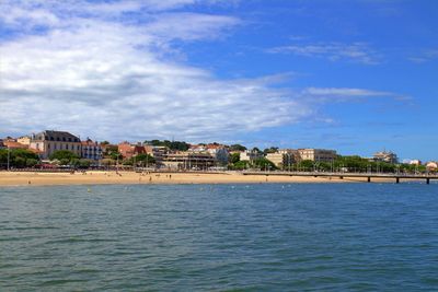 Scenic view of sea by buildings in town against sky