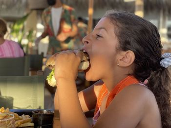 Profile view of girl biting and eating a sandwich 