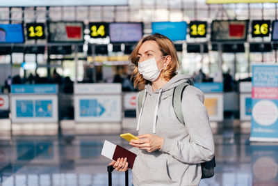 Woman holding mobile phone while standing on bus