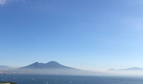 Scenic view of sea and mountains against clear blue sky