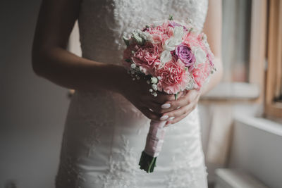 Midsection of bride holding bouquet