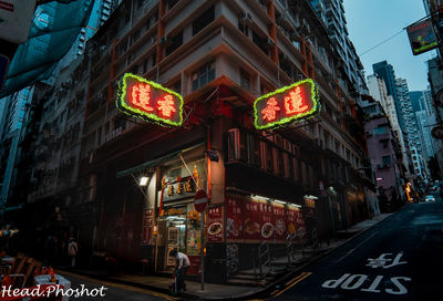 Road sign on street amidst buildings in city at night