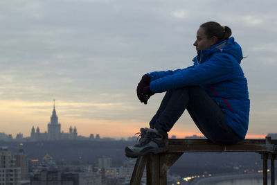 Boy looking at cityscape against sky