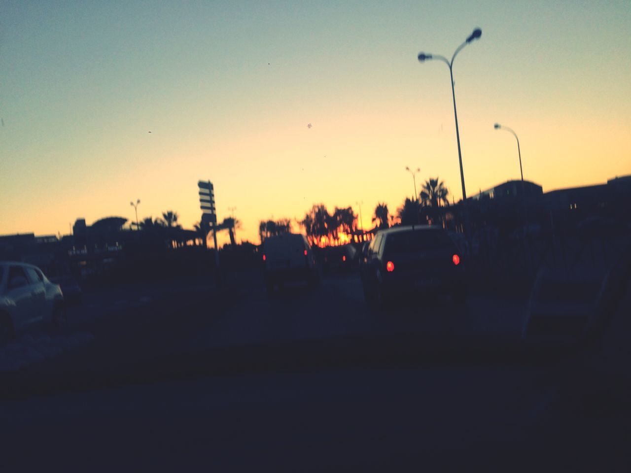 SILHOUETTE OF CARS ON ROAD AT SUNSET