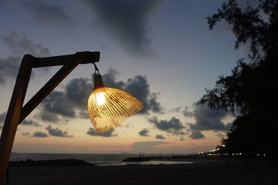 Low angle view of illuminated lighting equipment on beach against sky