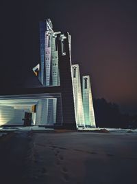 Illuminated buildings by sea against sky at night