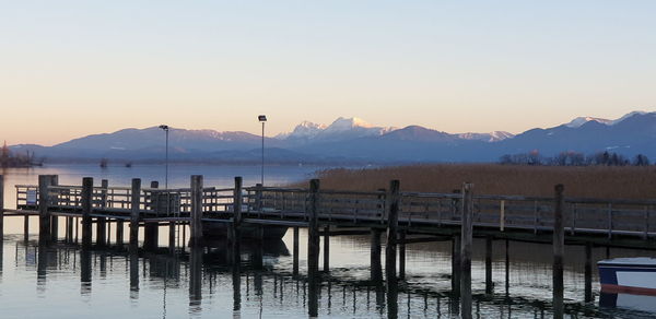 Pier on lake against sky during sunset