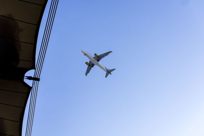 Low angle view of airplane flying against clear blue sky