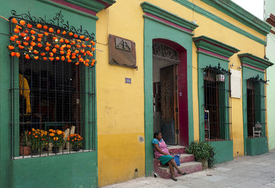 Full length of woman sitting outside building