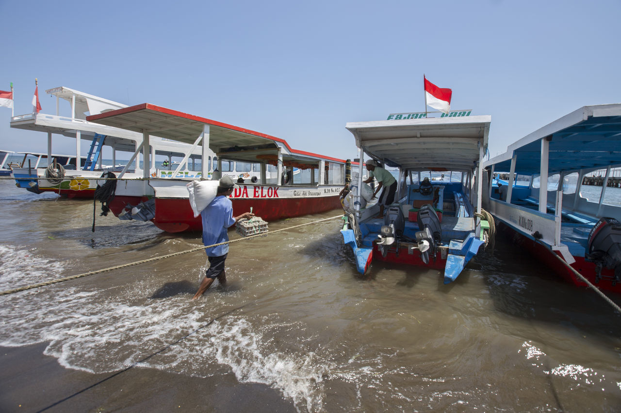 REAR VIEW OF PEOPLE ON BOAT AGAINST SKY