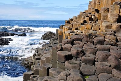 Rock formations at giant causeway by sea against sky