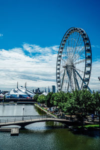 Ferris wheel by river against sky