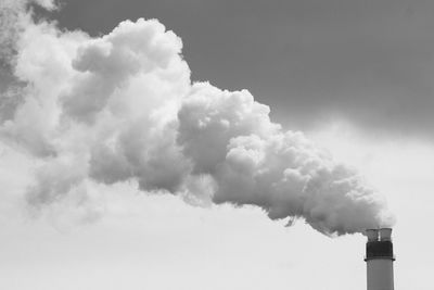 Low angle view of smoke emitting from chimney against sky