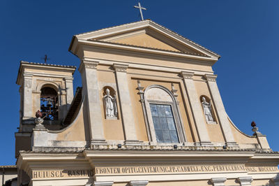 Low angle view of sculptures on building against clear blue sky